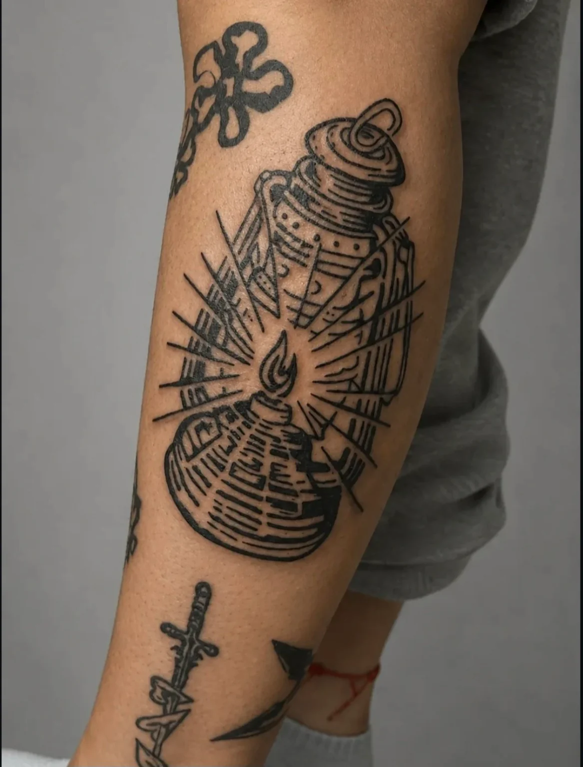 Tatuaje de un farol encendido con rayos de luz y sombreado de líneas en negro.