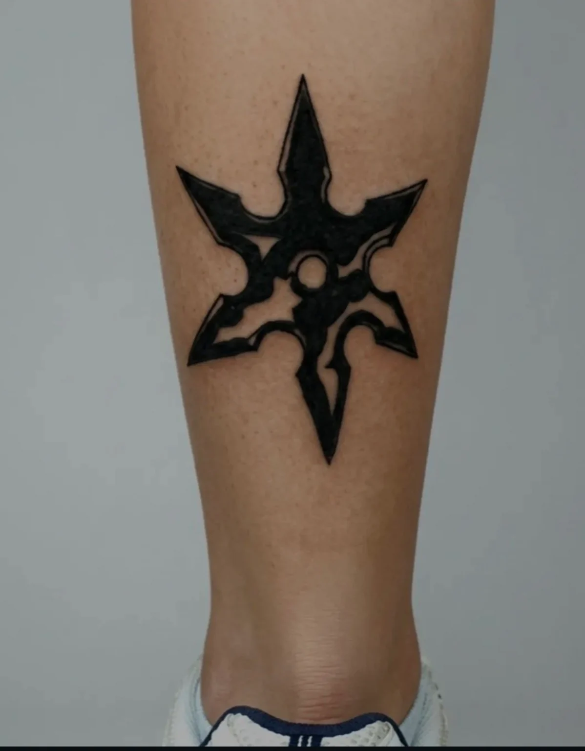 Tatuaje de un shuriken de seis puntas con rellenos negros.