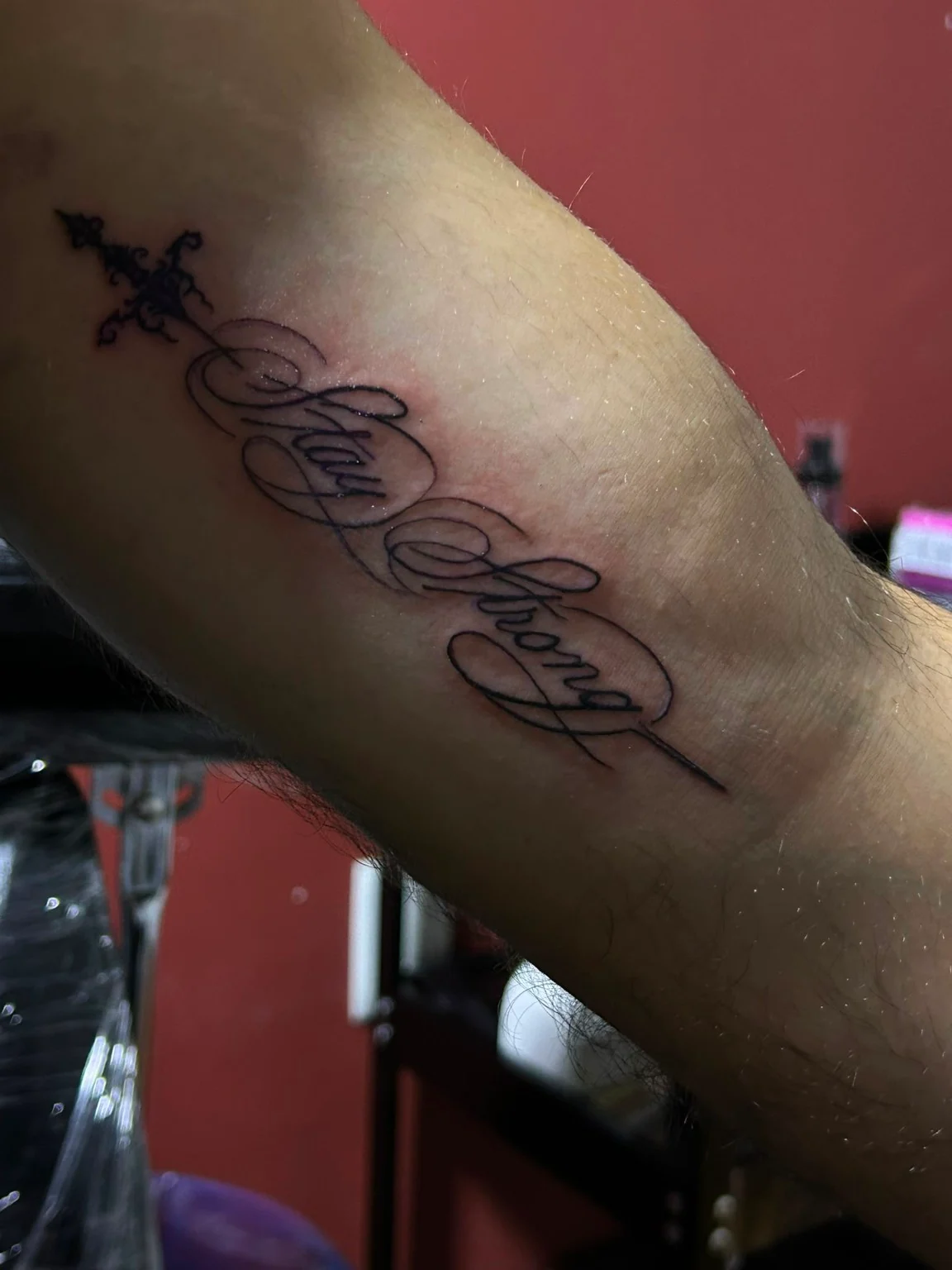 Lettering Stay Strong en letra caligráfica, con trazos ornamentales y una cruz.